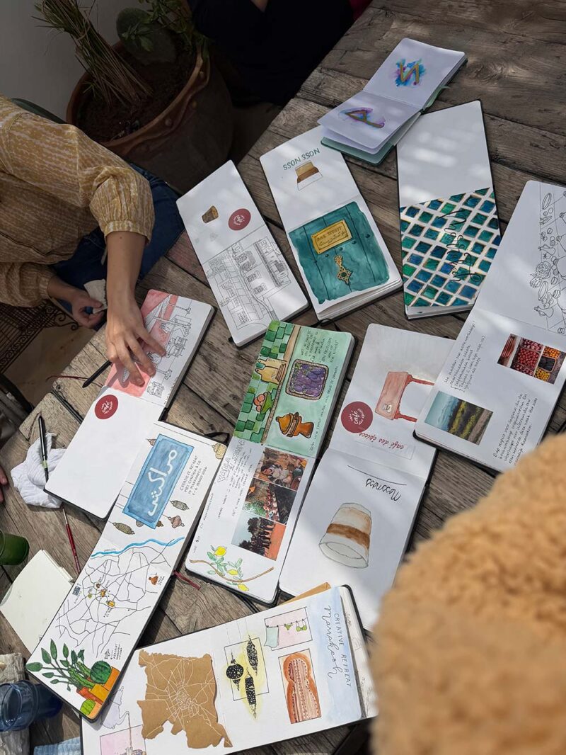 Travel journals van de deelnemers, opengeslagen op tafel