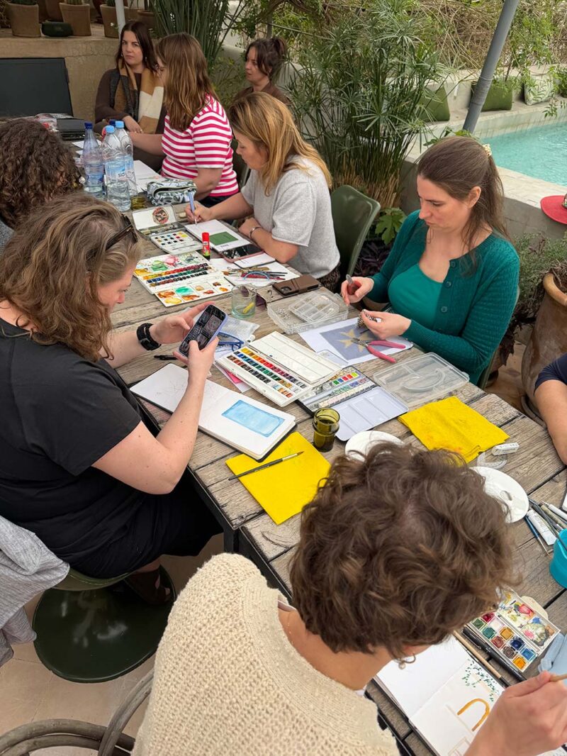 Tekensessie met de groep aan de lange tafel bij het water